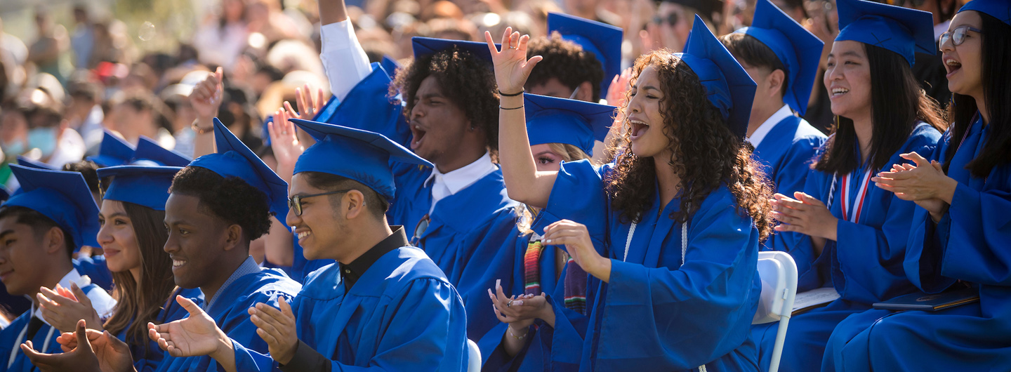 Graduating students in their cap and gowns cheering