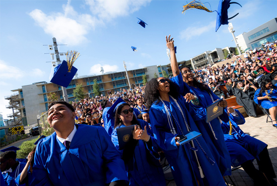 Graduates smile and cheer at the end of the commencement ceremony.